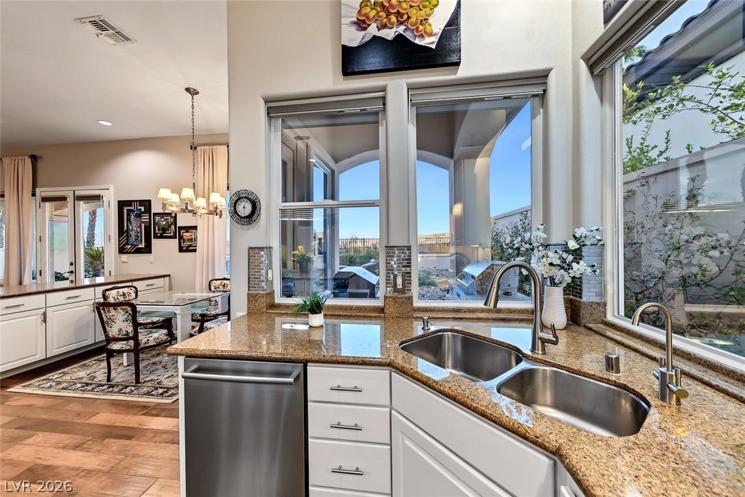 Granite counters and stainless steel appliances elevate this open kitchen overlooking the backyard.