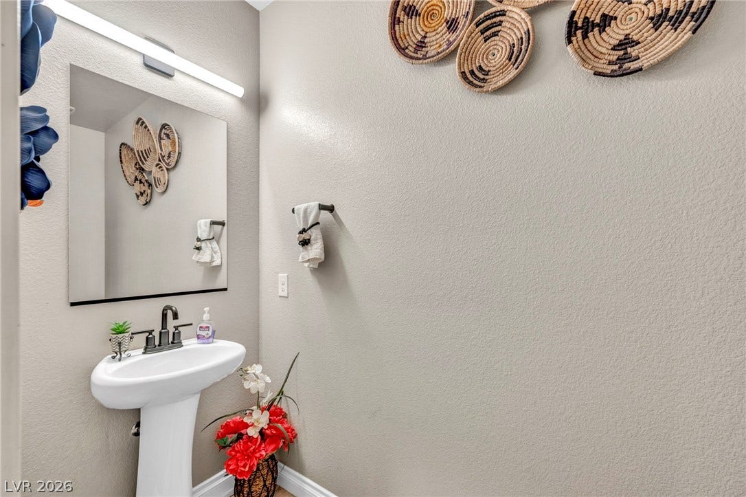 7481 Garnet Moon Street, North Las Vegas, NV 89084 A minimalist pedestal sink and sleek modern lighting grace this elegant powder room.