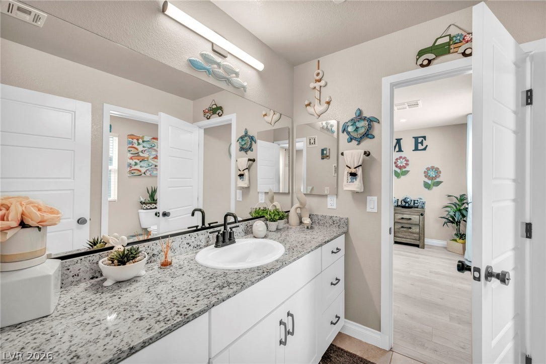 7481 Garnet Moon Street, North Las Vegas, NV 89084 Polished stone countertops pair with clean cabinetry in this well-appointed bathroom.