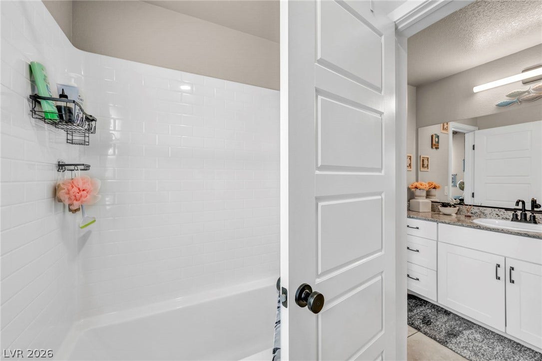 7481 Garnet Moon Street, North Las Vegas, NV 89084 Crisp subway tile surrounds the built-in tub next to a modern vanity bathroom.