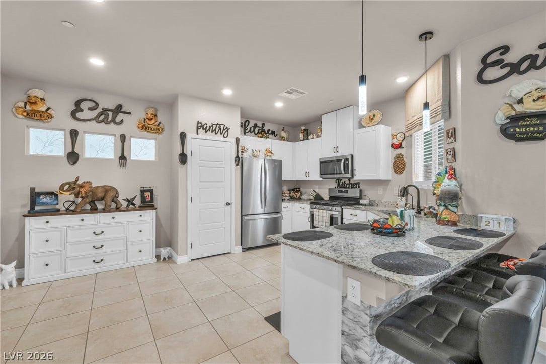7481 Garnet Moon Street, North Las Vegas, NV 89084 White cabinetry, stone countertops, and tile flooring define this modern cooking space.