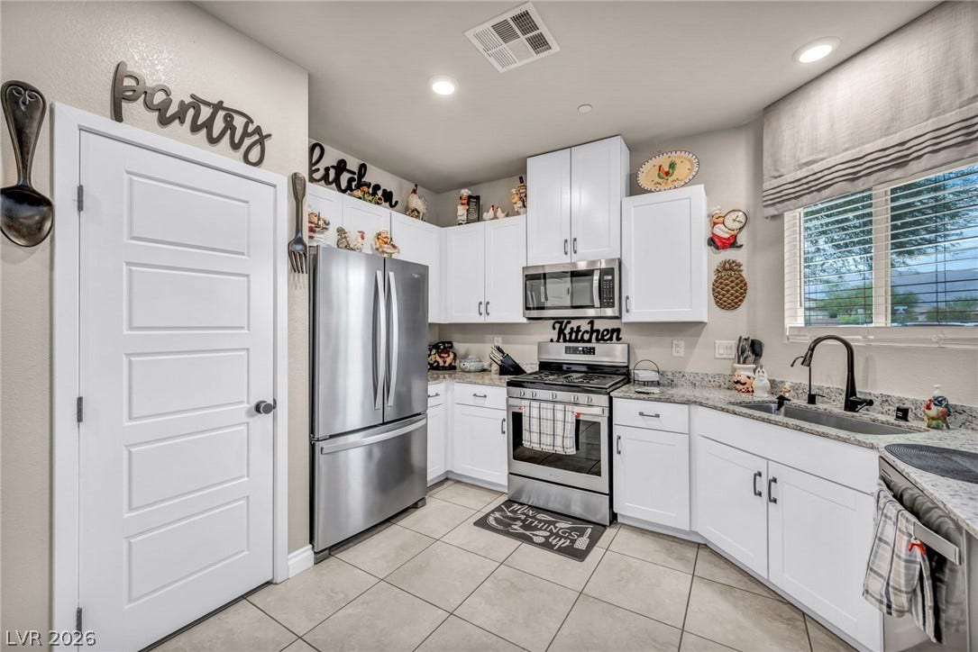 7481 Garnet Moon Street, North Las Vegas, NV 89084 White cabinetry paired with granite countertops and stainless steel appliances forms a classic culinary workspace.