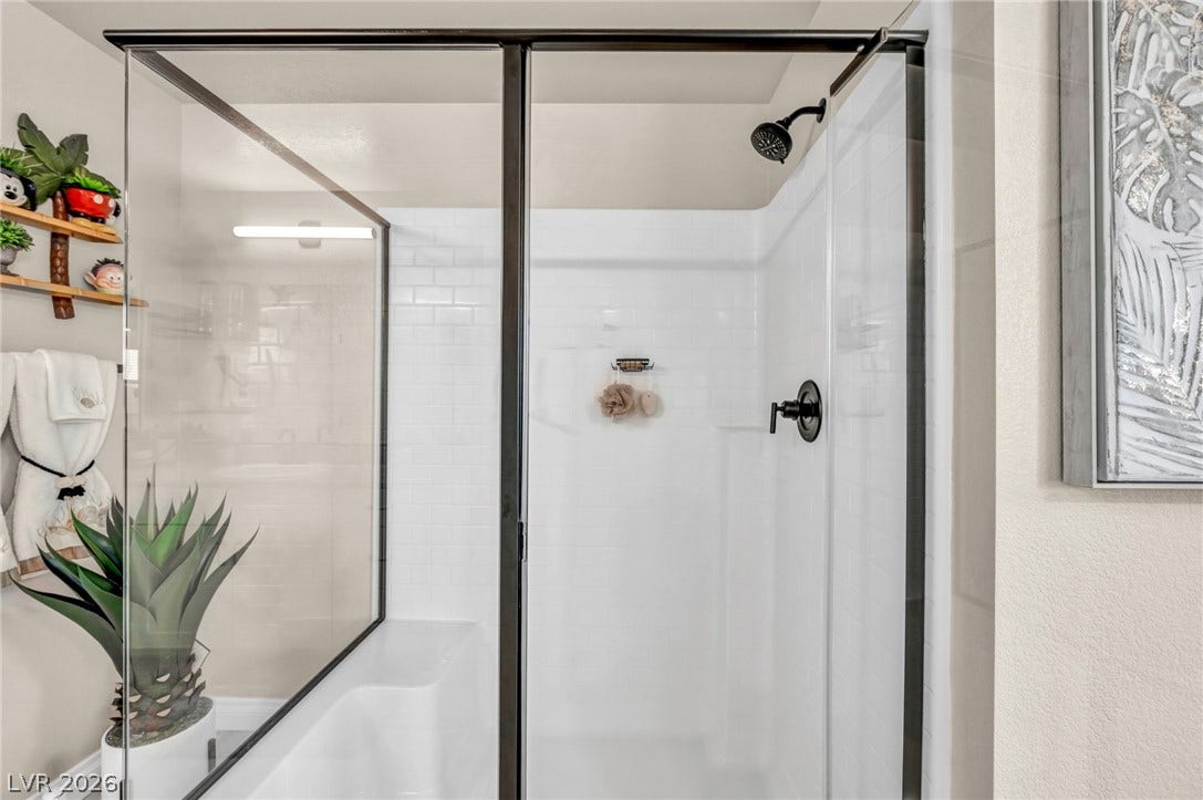 7481 Garnet Moon Street, North Las Vegas, NV 89084 A modern walk-in shower with white subway tile details and a dark metal frame.
