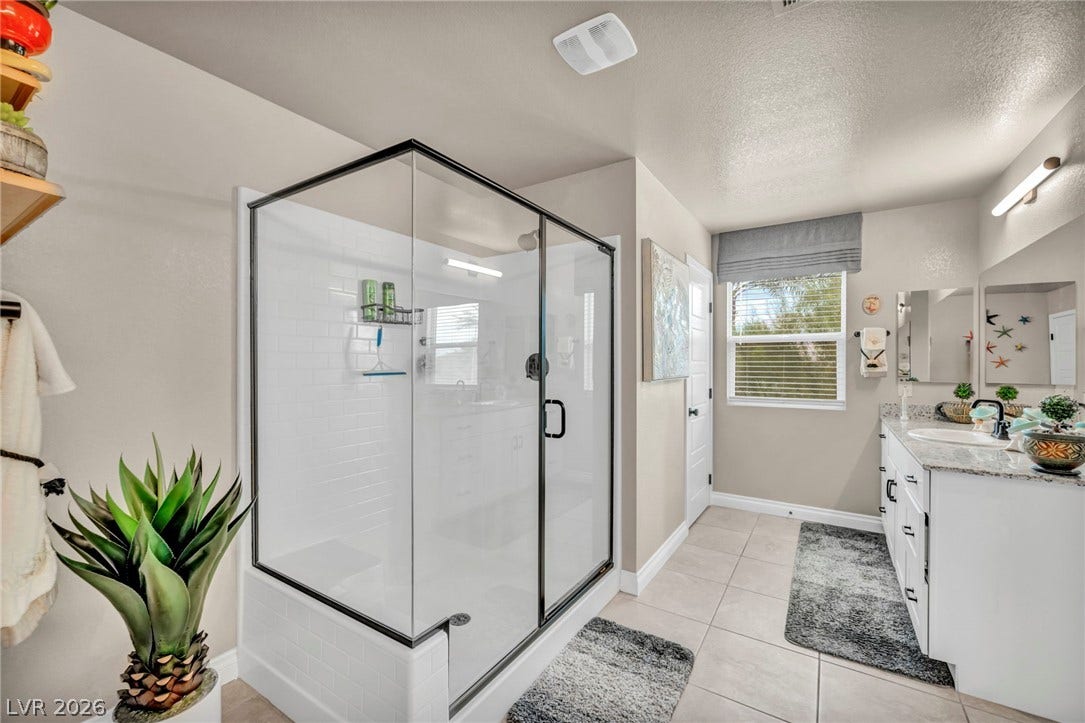 7481 Garnet Moon Street, North Las Vegas, NV 89084 Tiled floors and a glass-enclosed walk-in shower elevate this updated bathroom design.