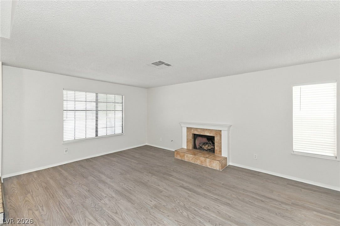 378 Tierra Street, Henderson, NV 89014 A classic wood-burning fireplace anchors this inviting room featuring wood-look flooring and multiple windows.