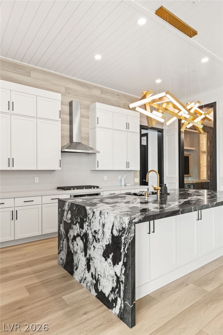 11041 Concord Valley Drive, Las Vegas, NV 89135 Dramatic stone counters anchor this gourmet kitchen featuring clean white cabinetry and warm wood flooring.