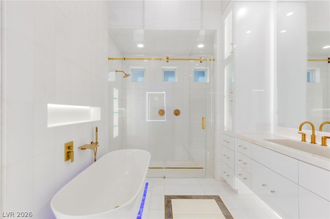 11041 Concord Valley Drive, Las Vegas, NV 89135 Sleek gold fixtures complement a freestanding tub and glass shower in this modern bath.