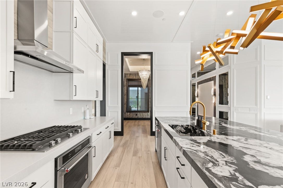 11041 Concord Valley Drive, Las Vegas, NV 89135 Crisp white cabinetry contrasts with a bold stone island beneath recessed lighting.