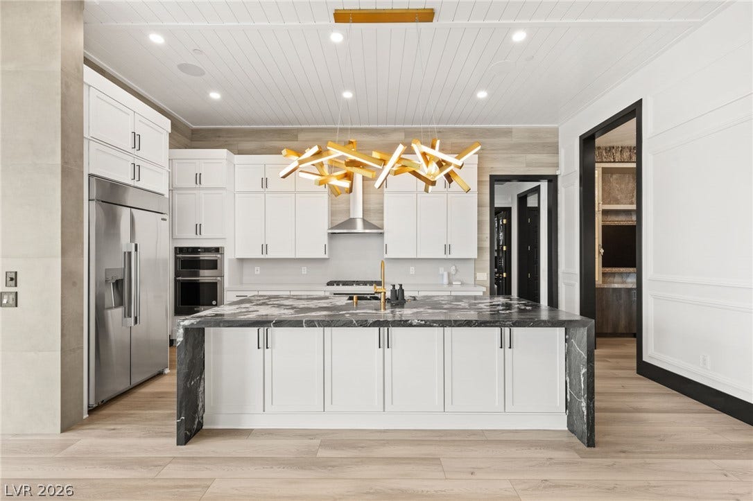 11041 Concord Valley Drive, Las Vegas, NV 89135 A spacious kitchen features a large dark stone island set against light hardwood flooring.