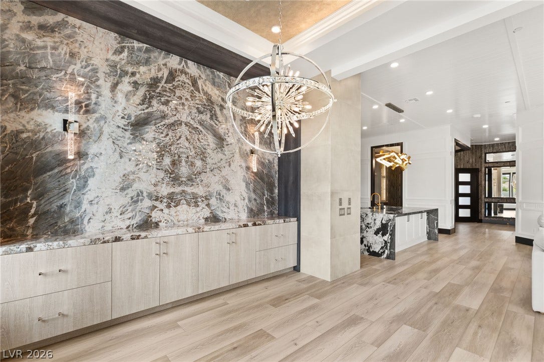 11041 Concord Valley Drive, Las Vegas, NV 89135 Gleaming hardwood floors and a bookmatched stone feature wall elevate this sophisticated open transition space.