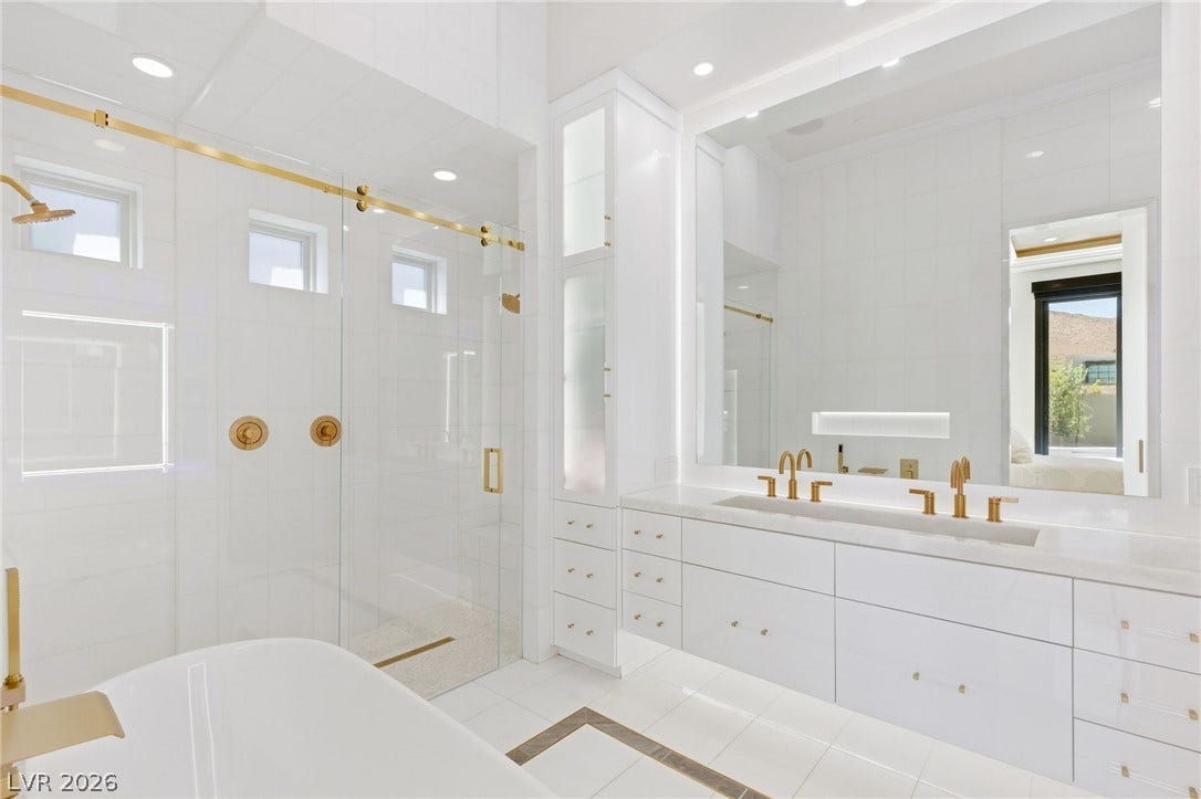11041 Concord Valley Drive, Las Vegas, NV 89135 Luxe brass accents elevate this modern washroom featuring a dual vanity and glass-enclosed shower.