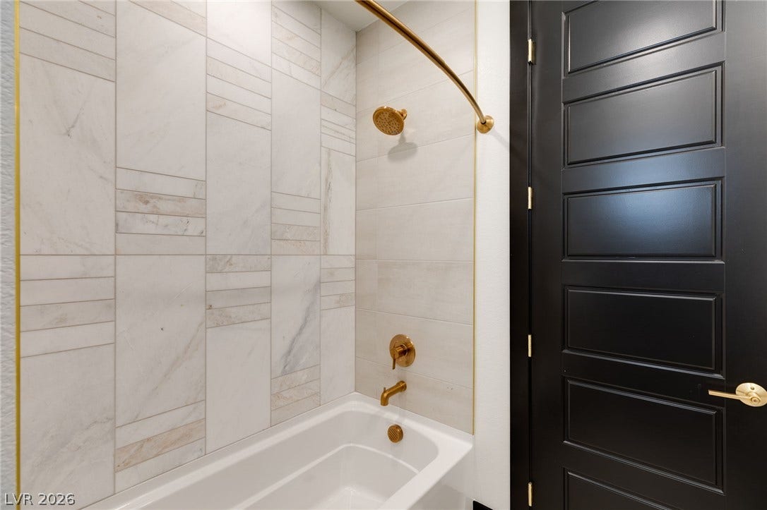 11041 Concord Valley Drive, Las Vegas, NV 89135 Sophisticated gold fixtures and floor-to-ceiling tiling elevate this modern bath.