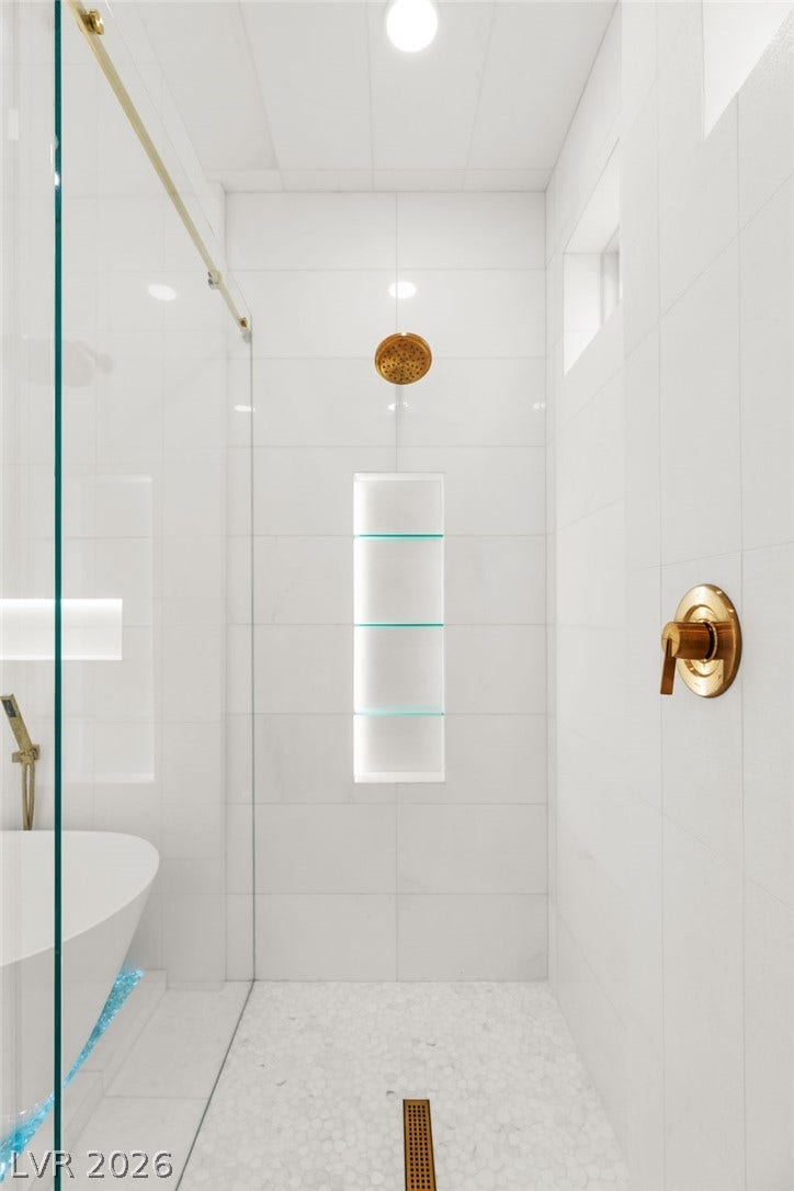 11041 Concord Valley Drive, Las Vegas, NV 89135 Gleaming gold fixtures elevate this walk-in shower lined with pristine white wall tiles.