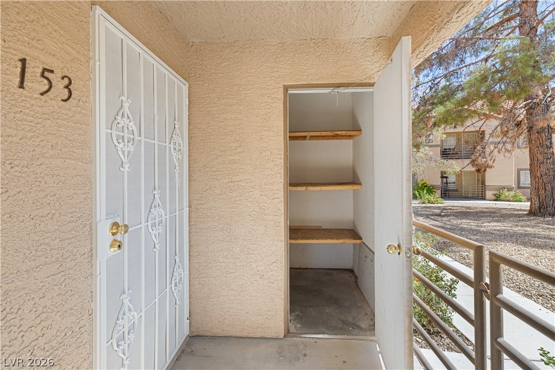 3450 Erva Street, #153, Las Vegas, NV 89117 A covered concrete patio area features a practical built-in outdoor storage closet with shelving.