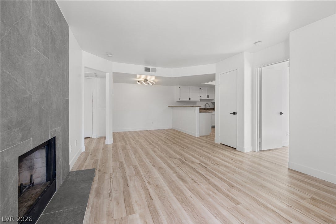 3450 Erva Street, #153, Las Vegas, NV 89117 Smooth wood-look flooring stretches across an airy, open layout anchored by a tiled fireplace wall.