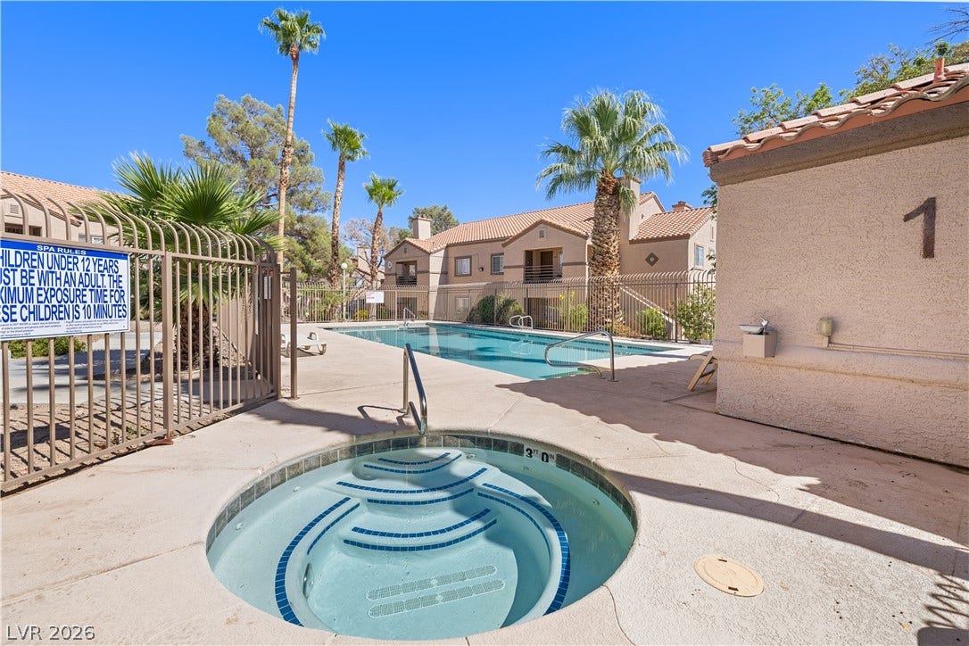 3450 Erva Street, #153, Las Vegas, NV 89117 An inviting outdoor spa and swimming pool area is surrounded by lush palm trees.