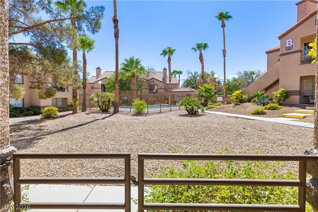 3450 Erva Street, #153, Las Vegas, NV 89117 A metal railing frames views of desert landscaping, palm trees, and the community pool area.