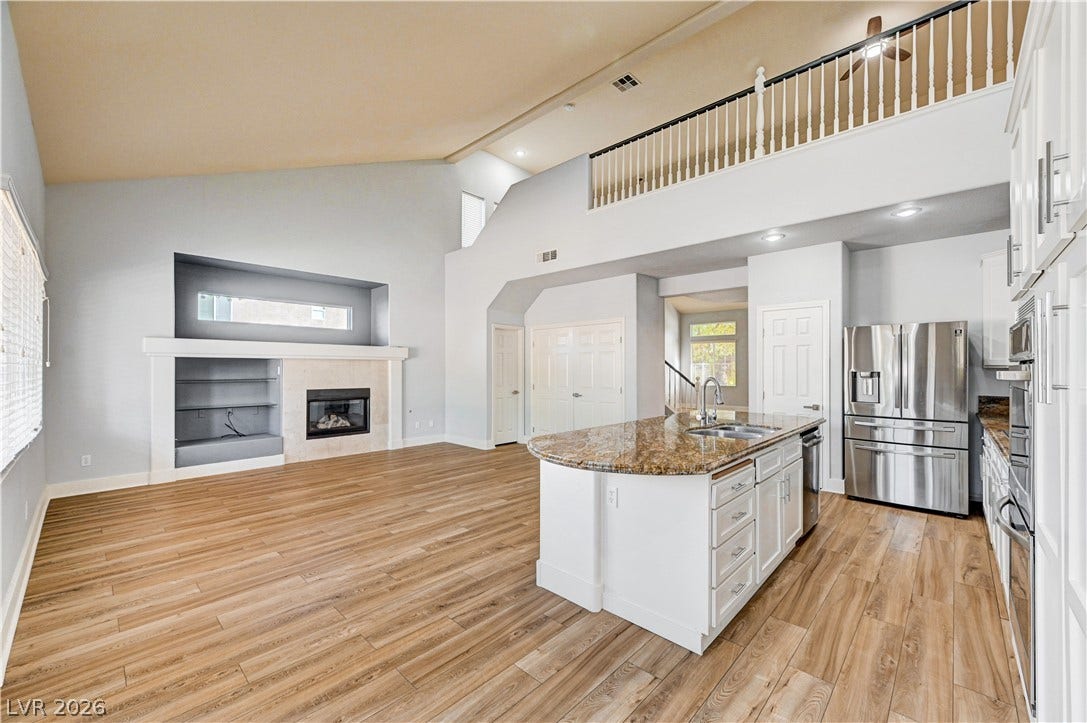 8908 Sheep Ranch Court, Las Vegas, NV 89143 Gleaming wood floors anchor a soaring double-height living space featuring an integrated open kitchen.