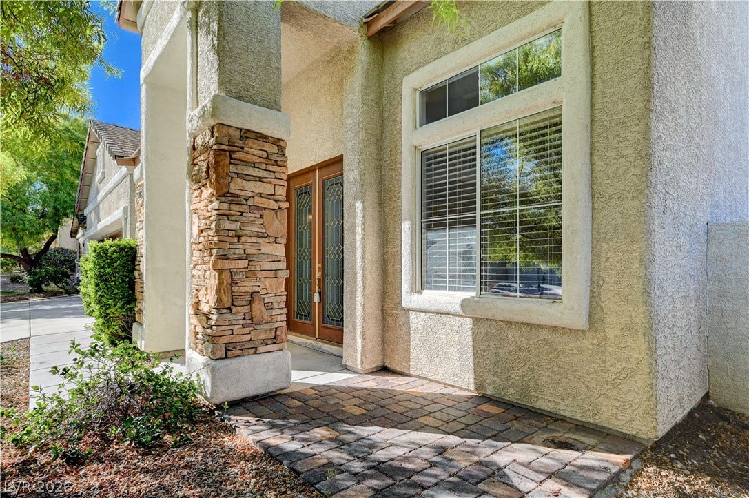 8908 Sheep Ranch Court, Las Vegas, NV 89143 Textured stucco and stone accents frame a welcoming entryway featuring elegant double glass doors.