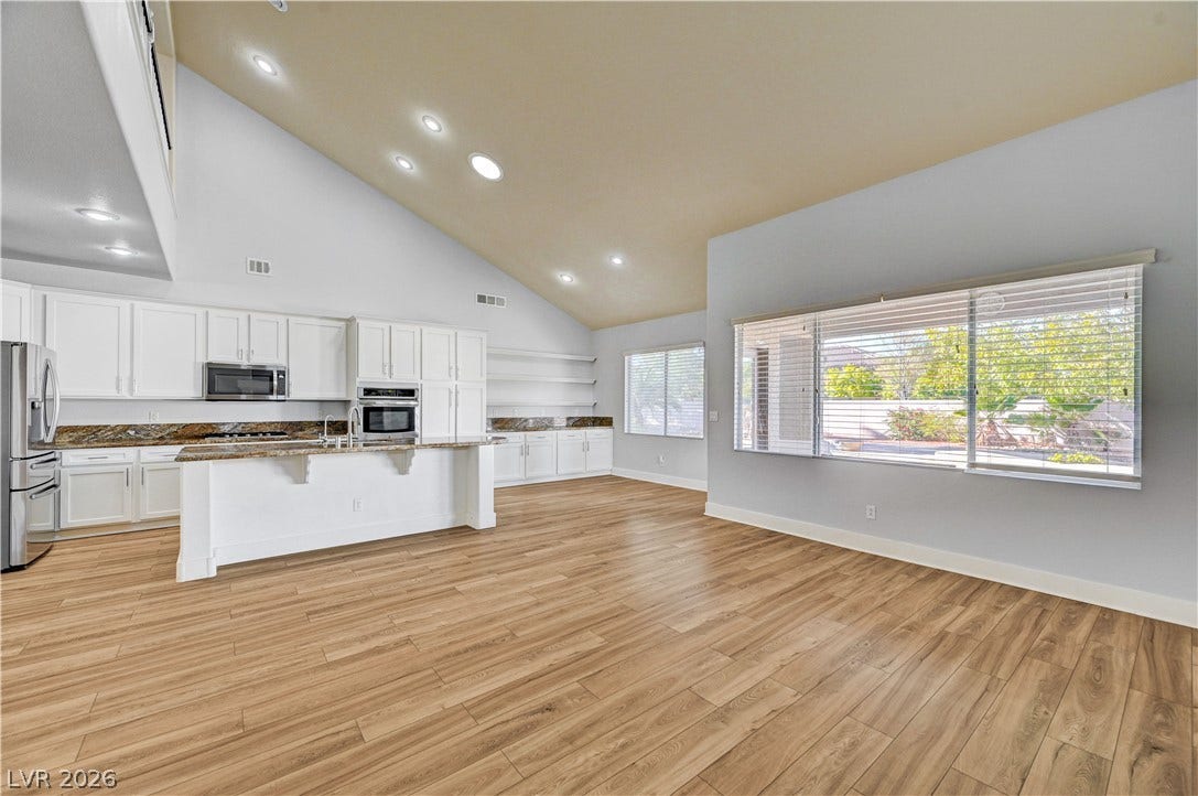 8908 Sheep Ranch Court, Las Vegas, NV 89143 Soaring vaulted ceilings and rich wood floors anchor this airy open concept kitchen and living space.
