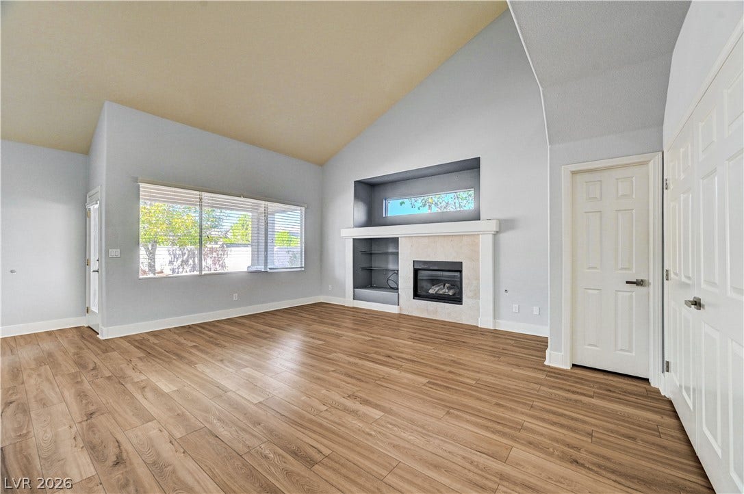 8908 Sheep Ranch Court, Las Vegas, NV 89143 Soaring vaulted ceilings and warm wood-style flooring anchor this open living area with its sleek fireplace.