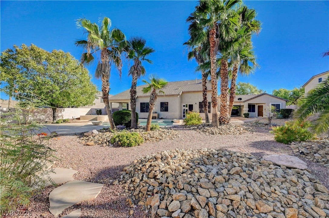 8908 Sheep Ranch Court, Las Vegas, NV 89143 Palm trees and desert landscaping frame the backyard pool and single-level stucco home.