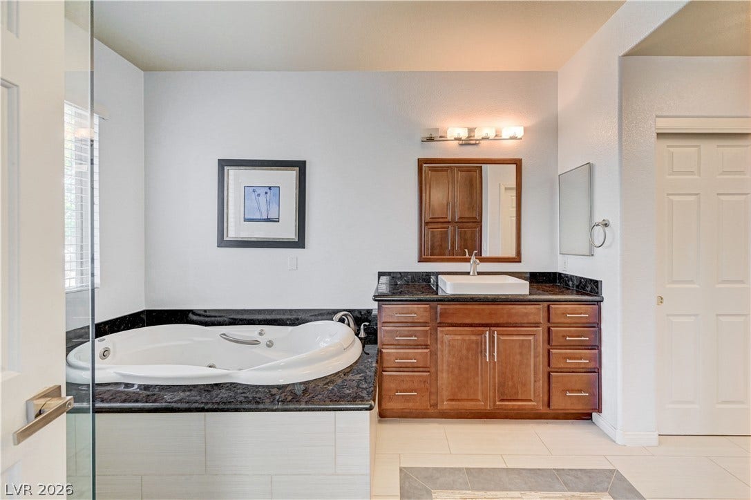 8908 Sheep Ranch Court, Las Vegas, NV 89143 Polished stone counters and a deep soaking tub anchor this serene primary bath retreat.