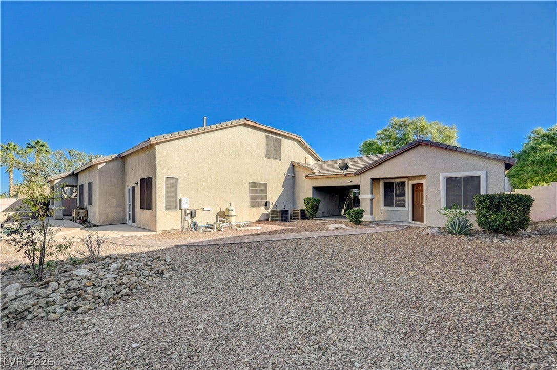 8908 Sheep Ranch Court, Las Vegas, NV 89143 A spacious desert landscape frames the back of this stucco residence under clear blue skies.