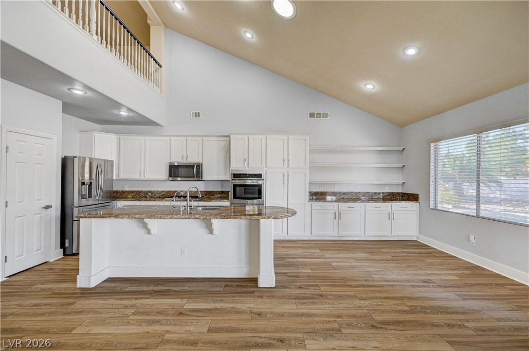 8908 Sheep Ranch Court, Las Vegas, NV 89143 Soaring vaulted ceilings and rich wood-style flooring elevate this modern, light-filled kitchen space.