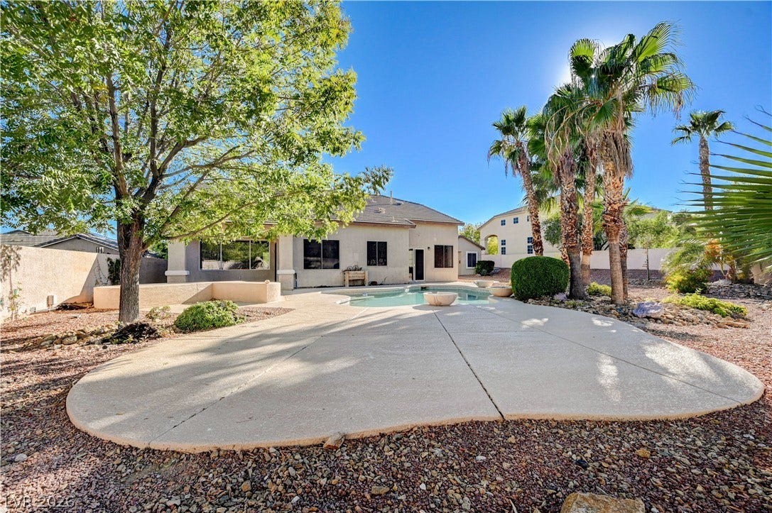 8908 Sheep Ranch Court, Las Vegas, NV 89143 A spacious concrete patio surrounds the sparkling backyard pool under mature palm trees.