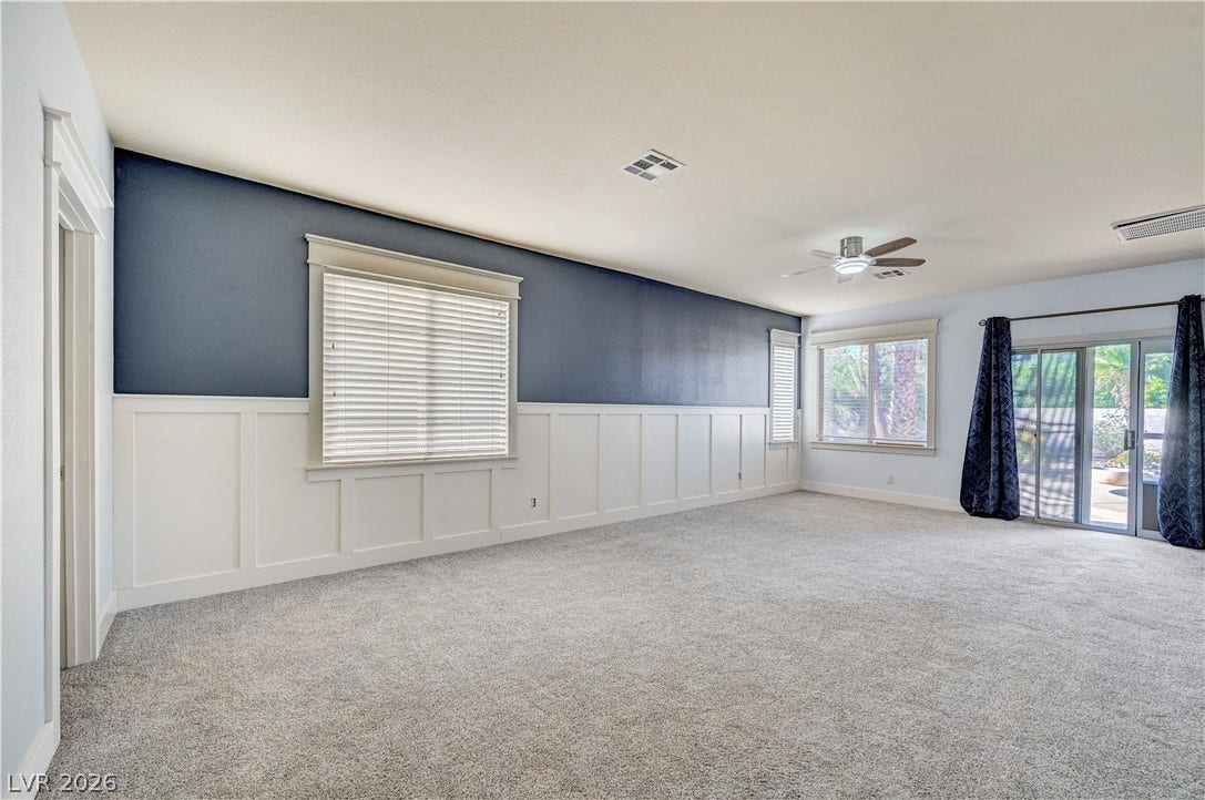8908 Sheep Ranch Court, Las Vegas, NV 89143 Plush carpeting and classic wainscoting define this versatile living space featuring sliding glass doors.