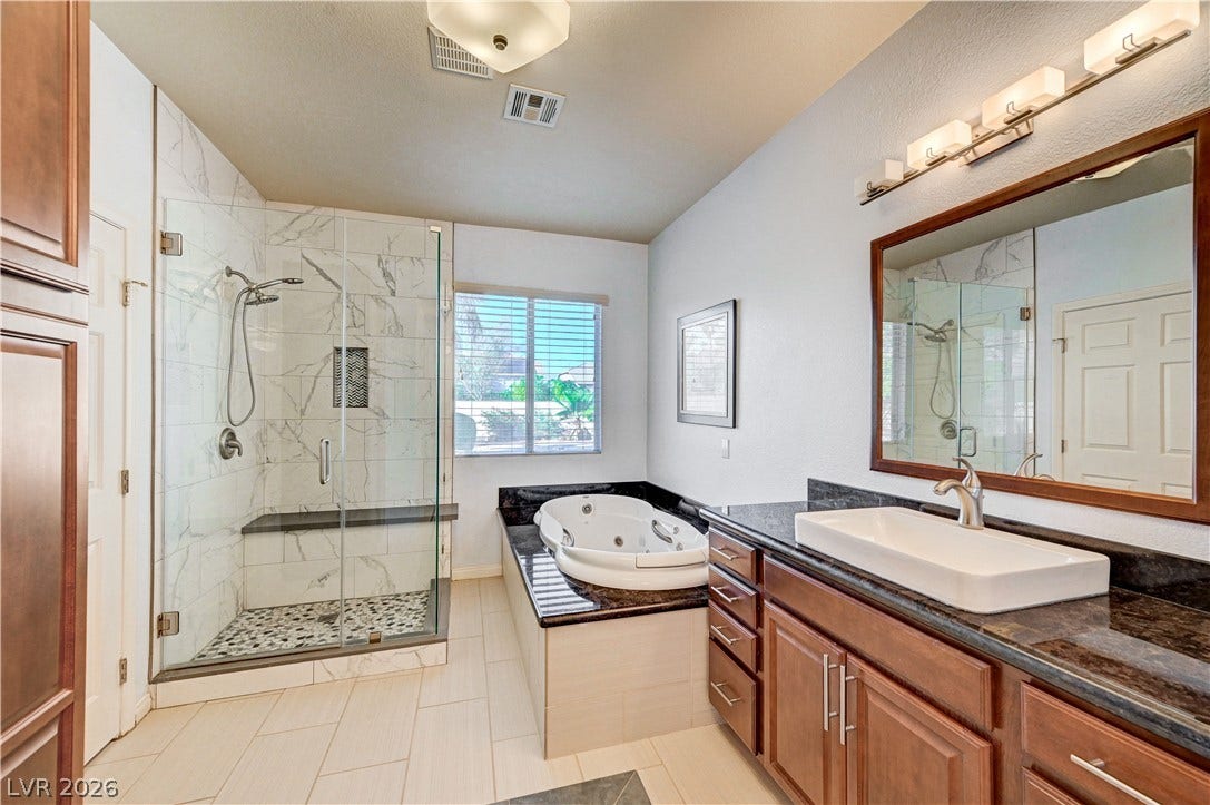 8908 Sheep Ranch Court, Las Vegas, NV 89143 An elegant soaking tub, glass-enclosed shower, and polished stone counters elevate this bathroom.