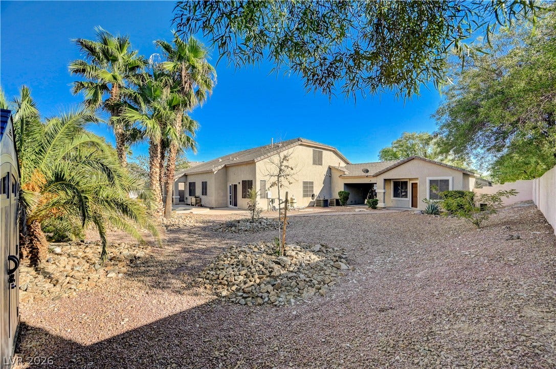 8908 Sheep Ranch Court, Las Vegas, NV 89143 Mature desert plantings and palm trees frame the expansive rear elevation of this stucco home.