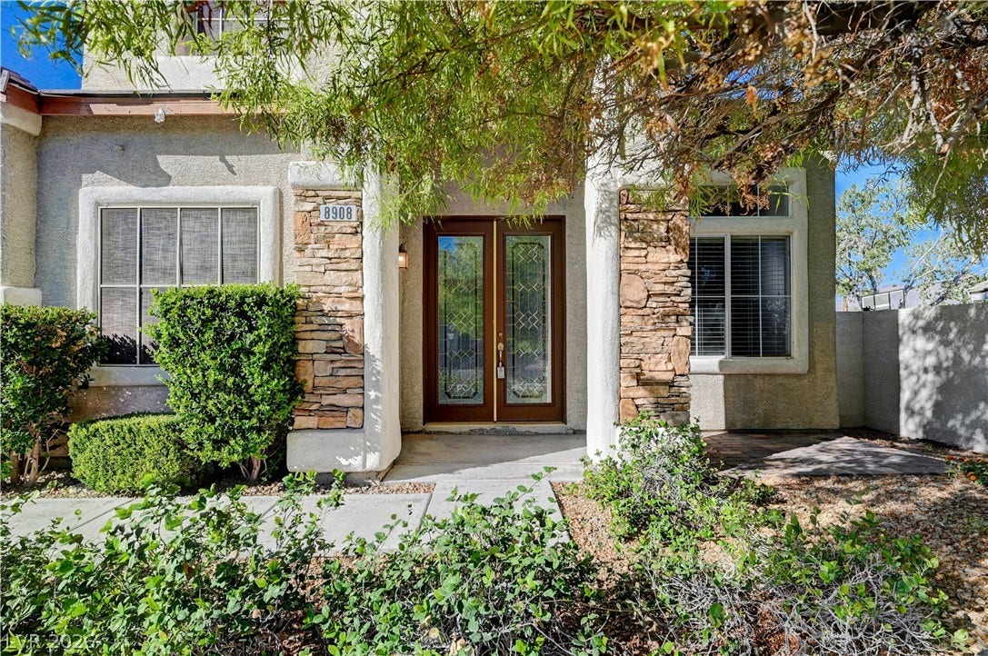 8908 Sheep Ranch Court, Las Vegas, NV 89143 Inviting glass-paneled double entry doors sit framed by textured stone accents and mature landscaping.