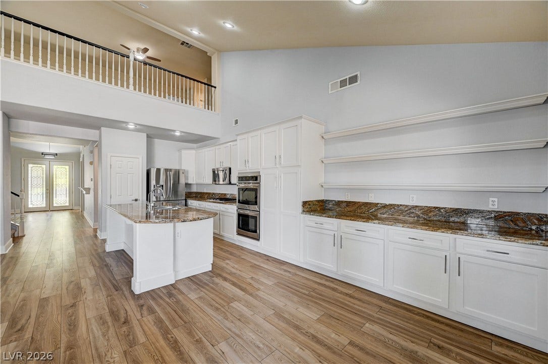 8908 Sheep Ranch Court, Las Vegas, NV 89143 Vaulted ceilings soar over a sprawling kitchen finished with granite countertops and rich wood flooring.
