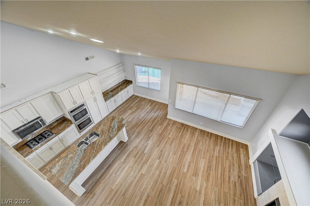 8908 Sheep Ranch Court, Las Vegas, NV 89143 Gleaming wood floors anchor a sprawling kitchen featuring custom granite counters and a majestic vaulted ceiling.
