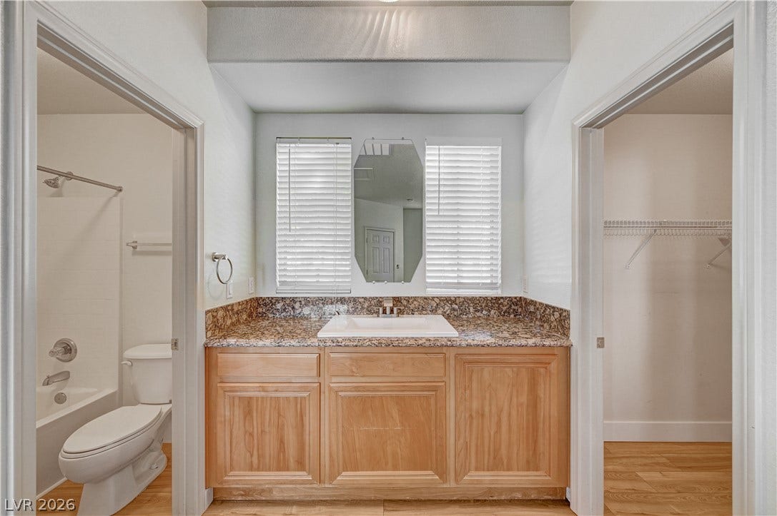 8908 Sheep Ranch Court, Las Vegas, NV 89143 Natural wood cabinetry and granite counters anchor this functional bathroom layout.
