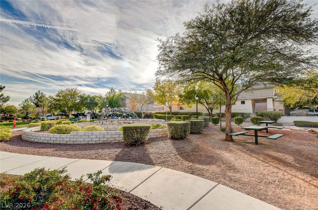 8908 Sheep Ranch Court, Las Vegas, NV 89143 A paved path leads past mature trees and a manicured play park under blue skies.