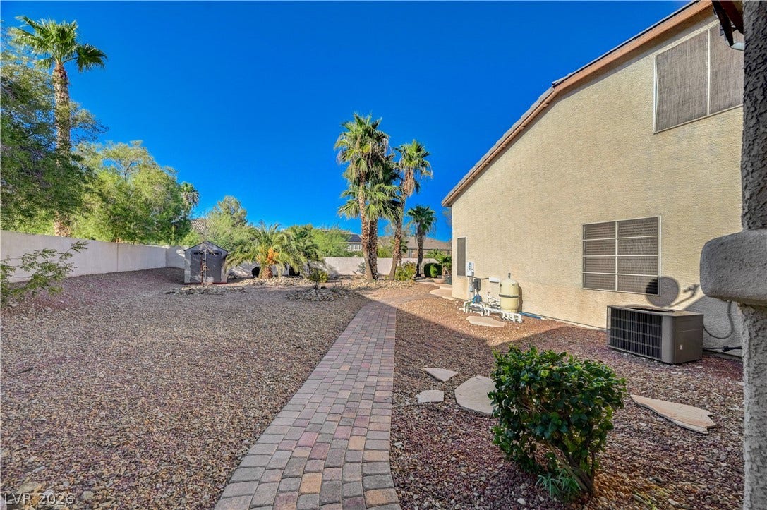 8908 Sheep Ranch Court, Las Vegas, NV 89143 A curved paver path leads through a low-maintenance gravel yard with mature palm trees.