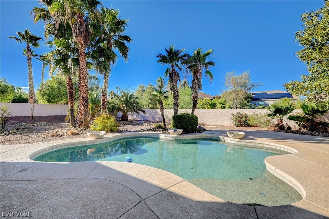 8908 Sheep Ranch Court, Las Vegas, NV 89143 Lush palm trees frame a sparkling pool surrounded by concrete decking and privacy walls.
