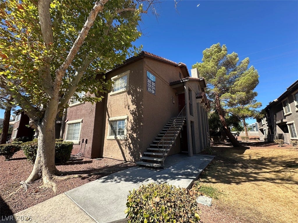 2750 S Durango Drive, #1014, Las Vegas, NV 89117 Mature trees shade the exterior of this multi-level residential building under clear blue skies.