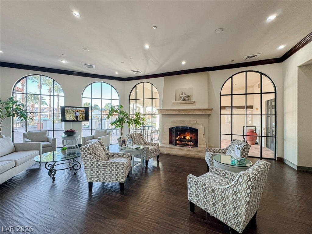 26 Strada Di Circolo, #n/a, Henderson, NV 89011 A stone fireplace accents this spacious room featuring dark wood flooring and arched windows.