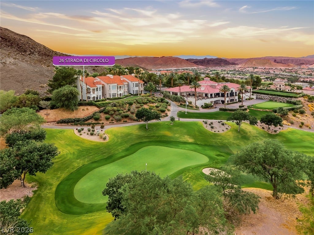 26 Strada Di Circolo, #n/a, Henderson, NV 89011 An aerial perspective showcases a red-tiled roof residence overlooking manicured golf fairways and mountain backdrops.