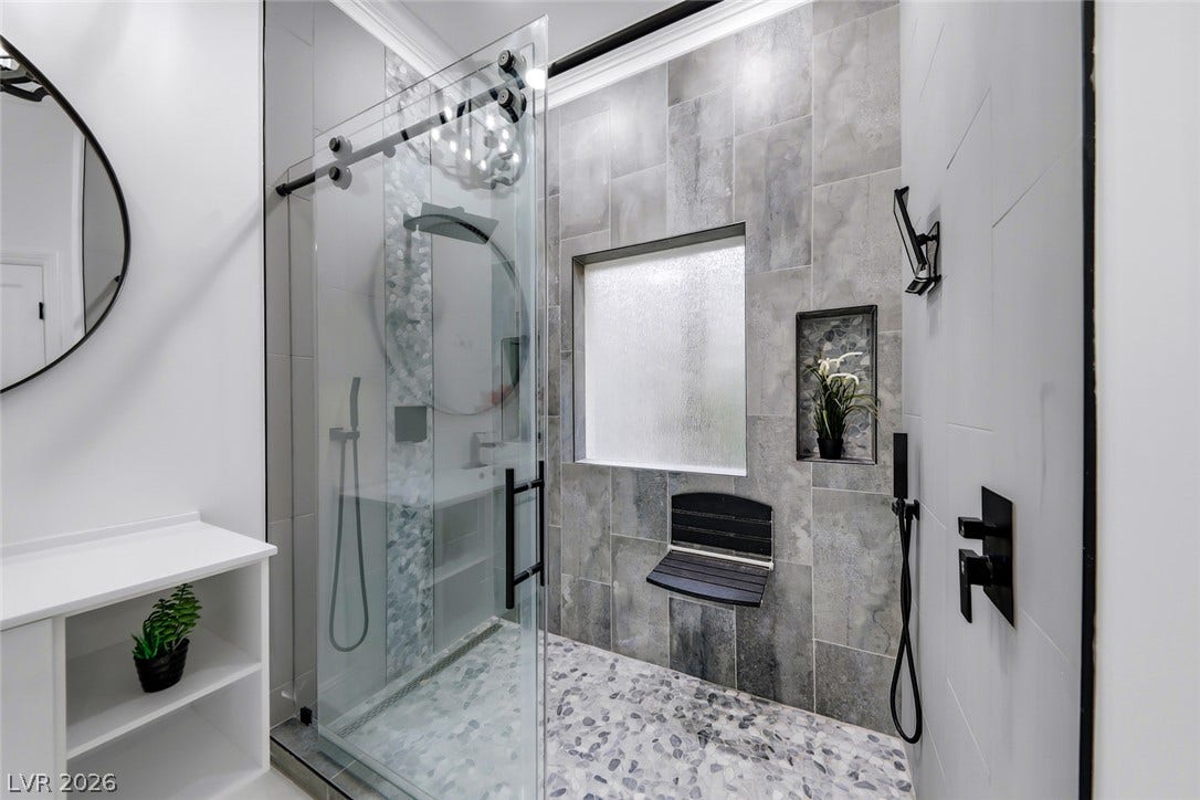 26 Strada Di Circolo, #n/a, Henderson, NV 89011 A modern walk-in shower features large-format wall tiles, pebble flooring, and a glass enclosure.