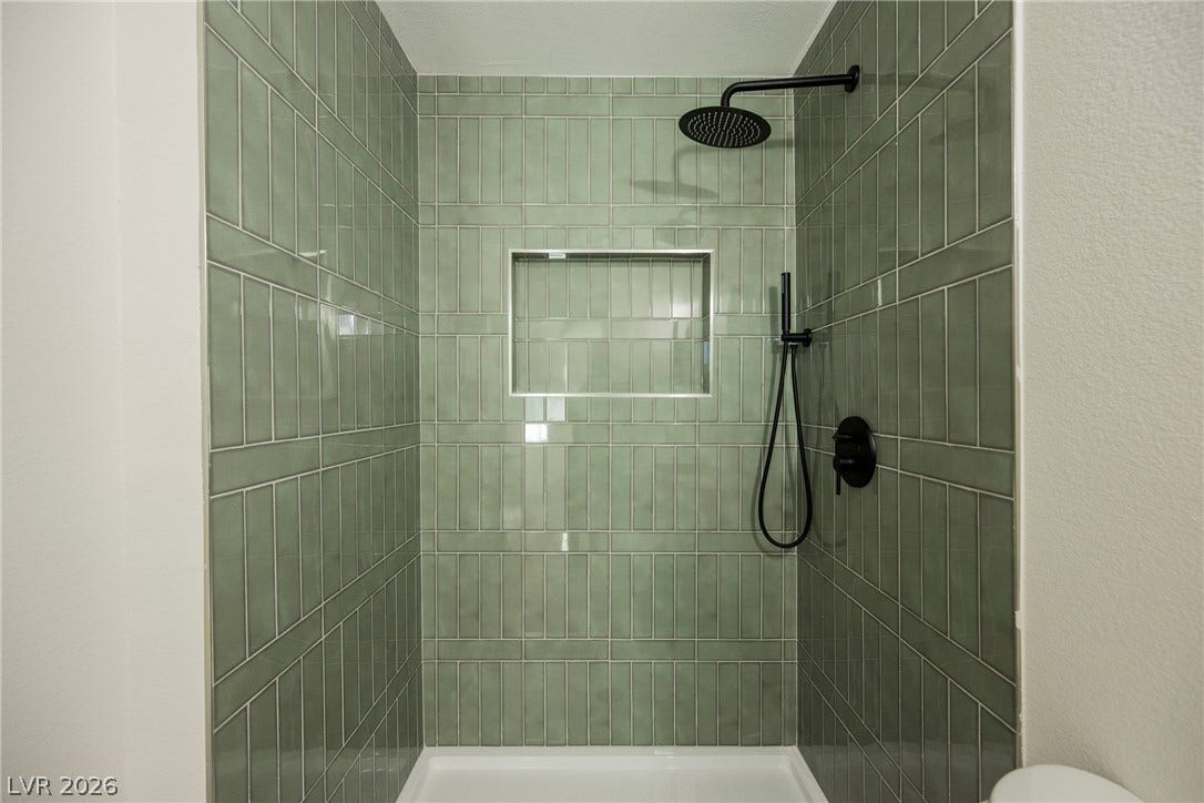 Custom vertical tiling and sleek matte black hardware create a refined walk-in shower experience.