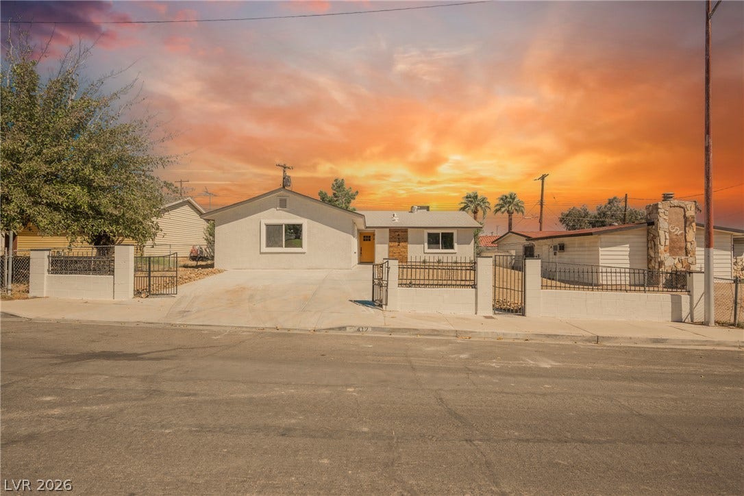 Smooth stucco and low-profile fencing frame this single-level home under a vibrant sky.