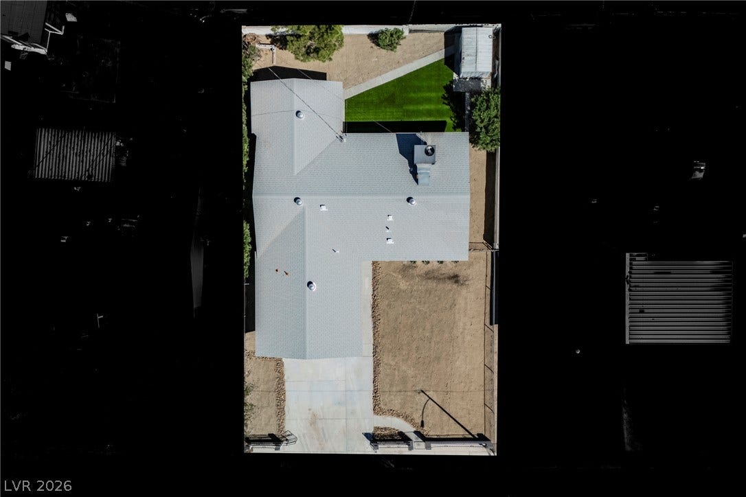 An aerial perspective showcases the shingle roof, concrete driveway, and structured fencing of this property.