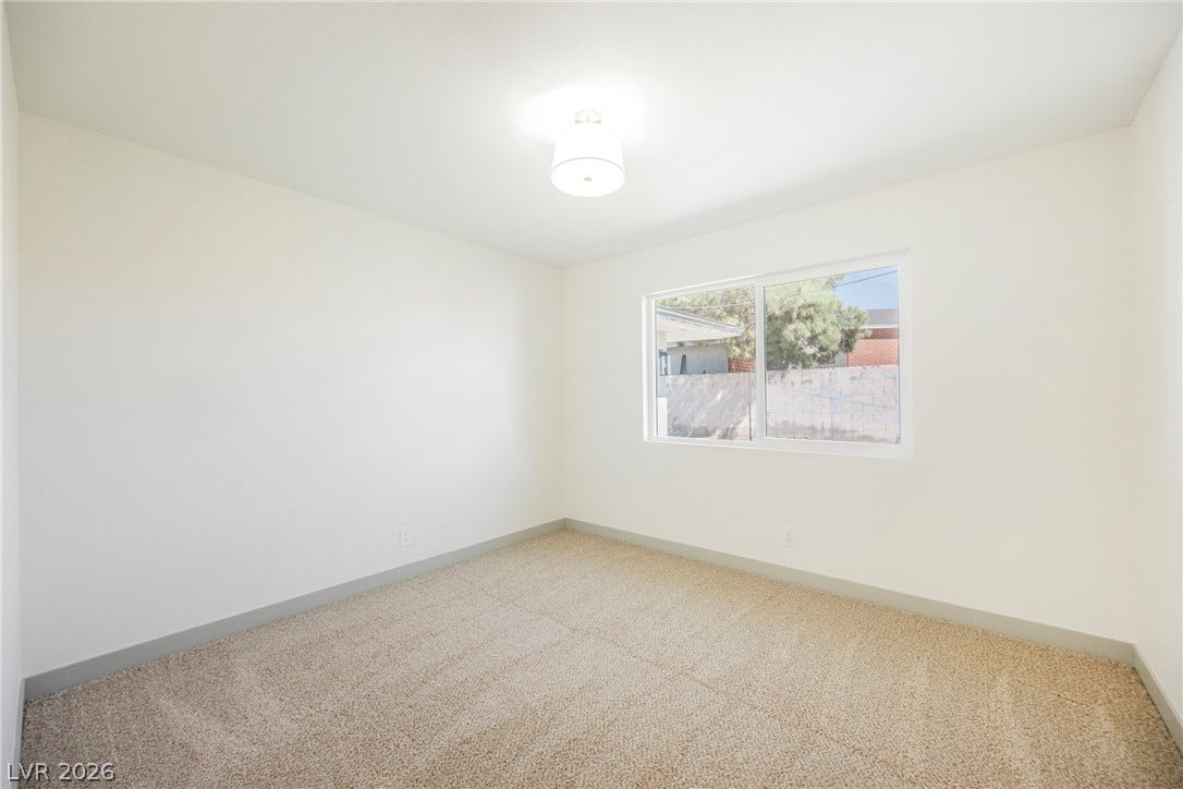 A single window illuminates a clean space with neutral carpeting.
