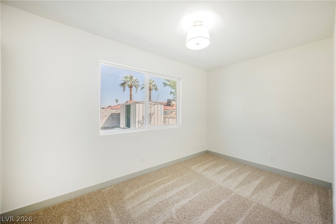 Plush carpeted flooring anchors this versatile bedroom space lit by a wide picture window.