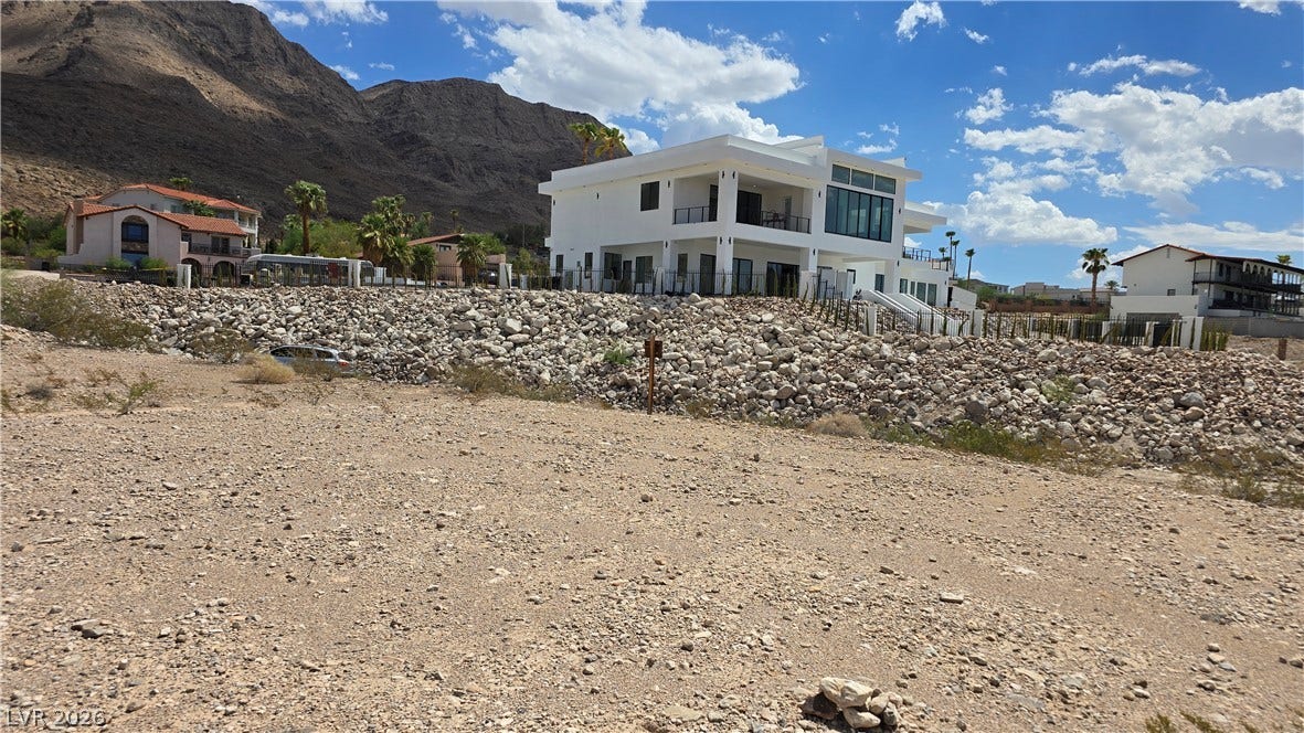 740 Benedict Drive, Las Vegas, NV 89110 Dramatic mountain backdrops frame a modern multi-level residence perched above a rugged desert landscape.